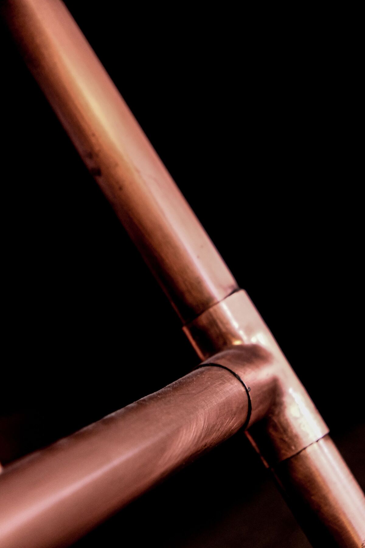 Detail měděných trubek na tmavém pozadí